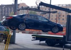 Эвакуатор с краном манипулятором эвакуирует легковое авто.