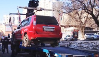 Процесс погрузки легкового автомобиля на эвакуатор краном-манипулятором.